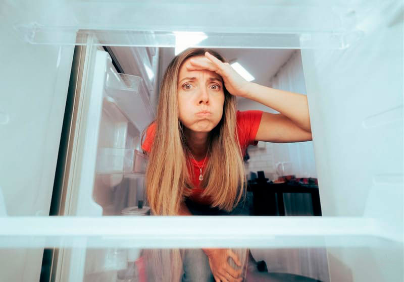 Persona frente a una heladera vacía